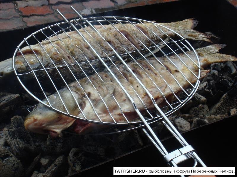 Рыба на костре на решетке на углях