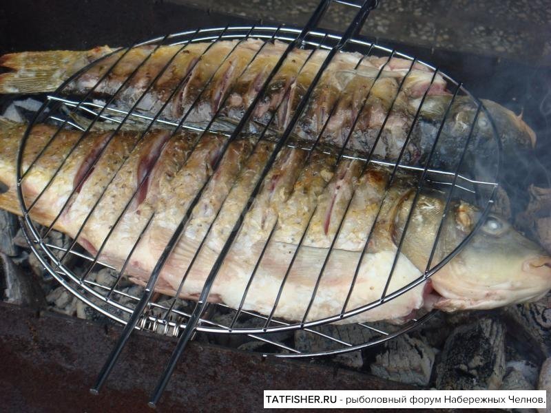 Рыба на костре на решетке на углях